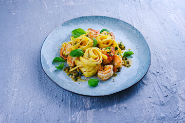 Traditional Italian tagliatelle ai gamberoni pasta with king prawns and herbs served as close-up on...
