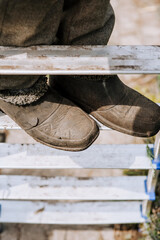 A worker, a man, a builder in a dirty robe stands on the steps of a metal stepladder outdoors. Photography, portrait of legs, shoe close-up, lifestyle, outdoor work.