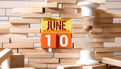 June 10 calendar date text on wooden blocks with blurred nature background. Copy space and calendar...
