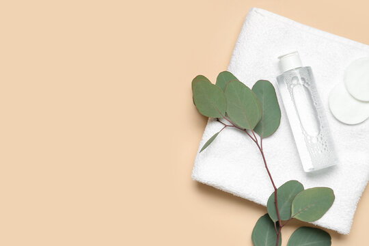 Bottle of micellar water with cotton pads, eucalyptus branch and towel on beige background