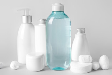 Micellar water with cosmetic products, cotton balls and pads on light background