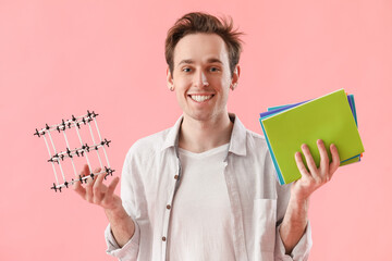 Male student with notebooks and model of crystal lattice on pink background