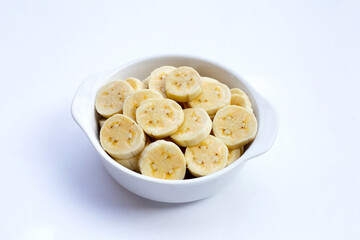 Banana slices in bowl on white background.
