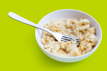 Mashed bananas in bowl on green background.