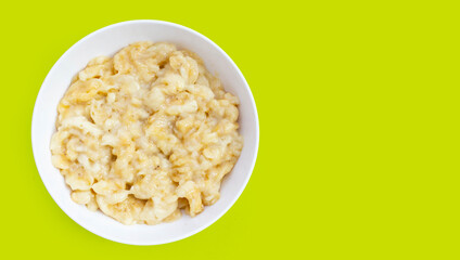 Mashed bananas in bowl on green background.