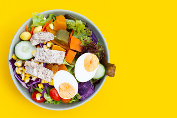 Salad with meat and vegetables on yellow background.