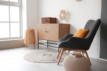 Interior of stylish living room with wooden cabinet and cozy armchair