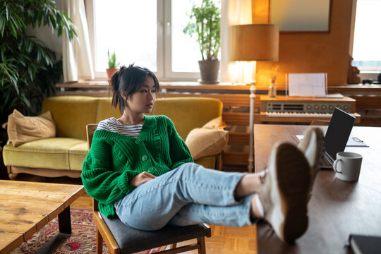 Asian girl in green shirt asitting with her feet up