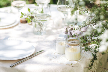 Rustic zero waste wedding decor with natural elements. Fresh spring blooming flowers, candles, linen napkins, wine glasses. Eco friendly decoration for the special holiday dinner. Romantic cozy place