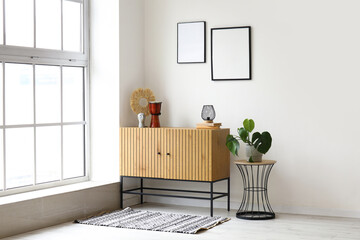 Stylish wooden cabinet and coffee table with houseplant near window