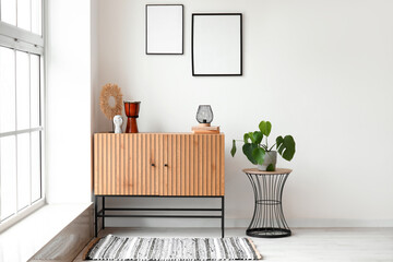 Stylish wooden cabinet and coffee table with houseplant near window