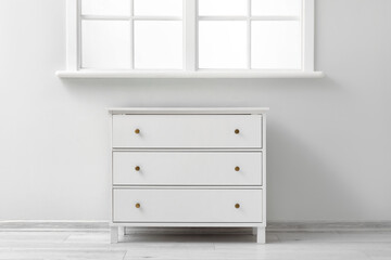 Stylish white chest of drawers near window