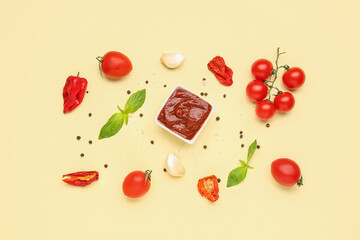Bowl of delicious tomato sauce and ingredients on yellow background