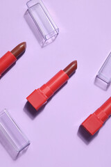 Red lipsticks on lilac background, closeup