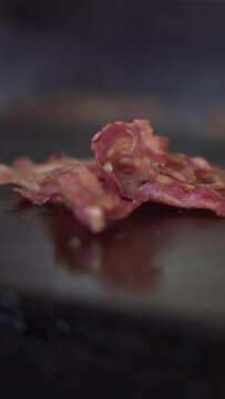 Bacon being cooked on a griddle for breakfast on a fast food restaurant