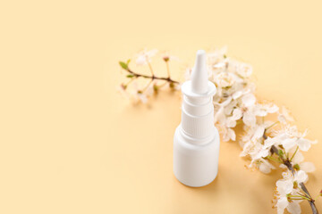 Nasal drops with blooming branch on beige background, closeup. Seasonal allergy concept