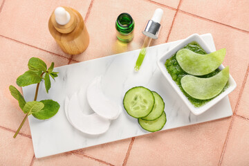 Cotton under-eye patches with cucumber slices and materials on beige tile background