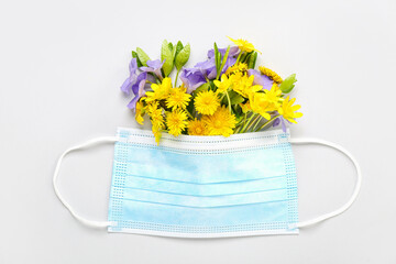 Medical mask with flowers on light background. Seasonal allergy concept