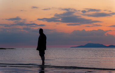 Silhouette of a man on the beach during sunset, photograph in orange tones.