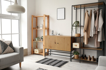 Interior of stylish living room with wooden cabinet, shelving unit and armchair