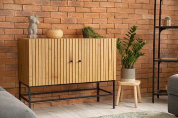 Stylish wooden cabinet near brown brick wall