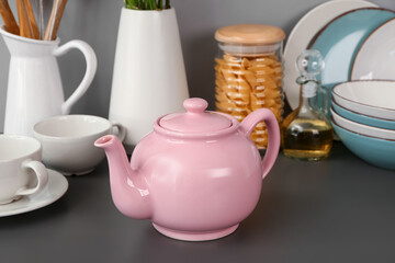 Composition with teapot, cups and different kitchen stuff on black table