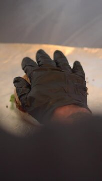 Preparing cheddar cheese and lettuce burgers with black gloves on fast food restaurant