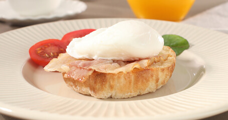 poached egg with bacon on a plate. boiled egg on bread with sauce. delicious breakfast with vegetables. serving food on a sunny day.