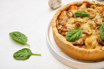 Mushroom pie with spinach leaves on white background