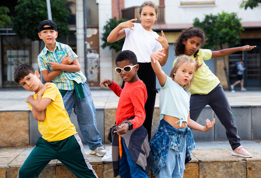 Group of children in casual clothes training hip-hop on street, learning modern dance movements
