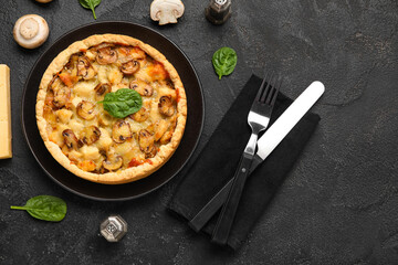 Mushroom pie with spinach leaves and cutlery on black grunge table