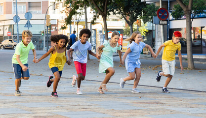 Fototapeta premium Happy children running together hand in hand through streets. Cheerful kids on summer vacation.