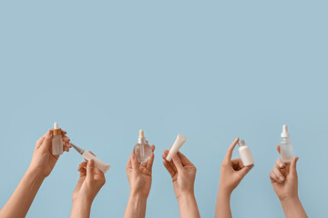 Hands holding different cosmetic products on light blue background