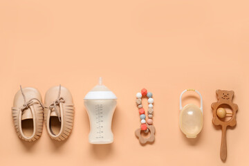 Bottle of milk for baby and accessories on pale orange background