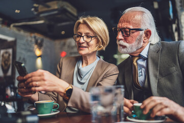 Loving Senior Couple Cherishing Sweet Moments at Cafe with Smartphones