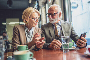 Happy Senior Couple Enjoying Digital Connection use smartphone at Cafe