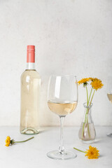 Bottle and glasses of dandelion wine on white table