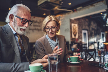 Happy Senior Couple Enjoying Digital Connection use smartphone at Cafe