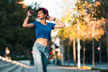 bella mujer adolescente estilo 80s 90s andando en skate en la ciudad, con maquillaje, anteojos y jeans. en un día soleado al atardecer.