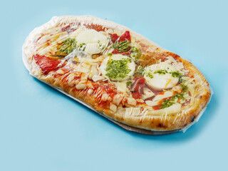 Italian style uncooked pizza on blue color background. Premium product with high quality ingredients.