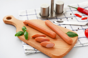 Board of tasty sausages and basil on grey background