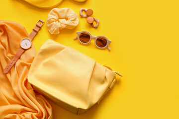 Stylish bag with watch and different accessories on yellow background