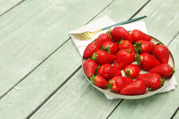 Plate with fresh strawberries on green wooden background
