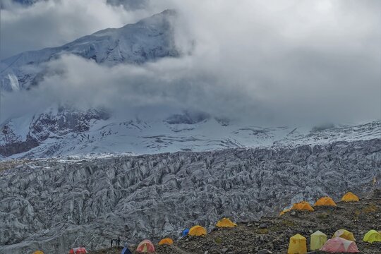 Colorful expedition tents stand at Manaslu Base Camp with the majestic Manaslu Glaciers forming a breathtaking backdrop. These vibrant tents create a captivating contrast against the icy glaciers.