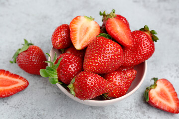 Bowl of fresh strawberries on grey grunge background