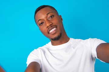 Photo of Handsome man wearing white T-shirt over blue background do selfie