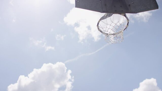 Variation of basketball travelling through the air before passing through the net of a hoop, in slow motion