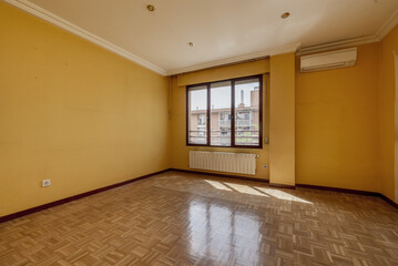 Empty living room with oak parquet, white aluminum radiators under a long