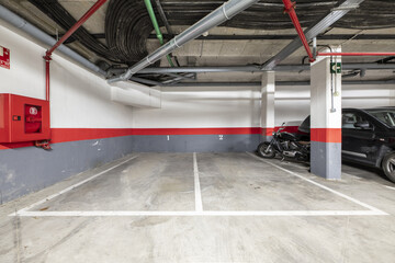 A few empty parking spaces in the basement of a residential building with red