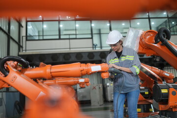 Robotic Arm engineer check on equipment in its with software of an Artificial Intelligence, .Female industrial engineer working at automated AI robotic production factory..